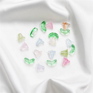 Close-up of translucent lily flower and leaf glass beads on white satin fabric