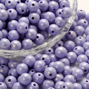 Macro view of lavender acrylic round beads with pearl luster spilling from a glass bowl