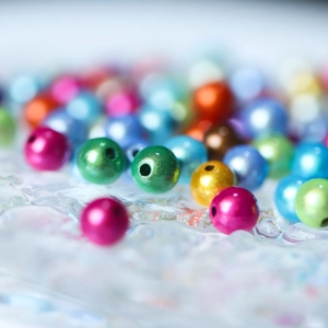 Vista macro di perle colorate iridescenti con finitura metallica per gioielli DIY