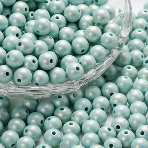 Macro detail of macaron light blue acrylic pearls with glossy finish in a glass bowl