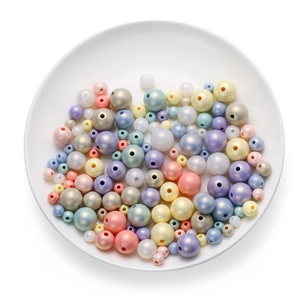 Macro shot of macaron colored pearl acrylic beads in a white dish for DIY jewelry
