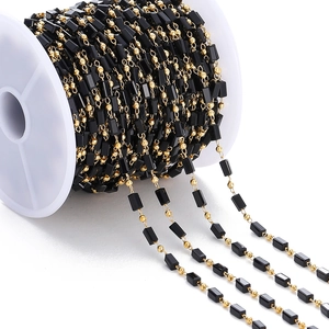 Detalle de cadena para joyas DIY con cuentas rectangulares negras y doradas en carrete