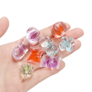 Macro shot of assorted colorful candy-shaped acrylic beads held in palm for DIY crafts