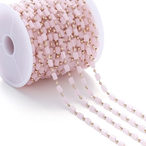 Rollo de cuentas cilíndricas rosas con cadena dorada para creación de joyas artesanales