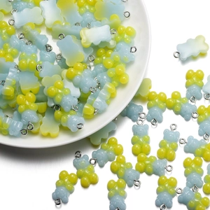 Macro detail of gradient yellow and blue resin bear charms with silver metal rings
