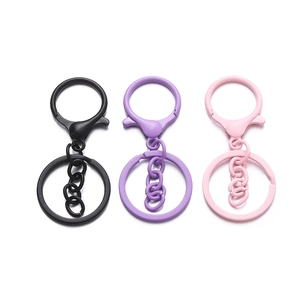 Dettaglio di moschettoni e portachiavi laccati opachi in nero, viola e rosa