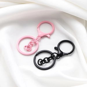 Dettaglio dei portachiavi laccati rosa e nero opaco con chiusure a moschettone e catene