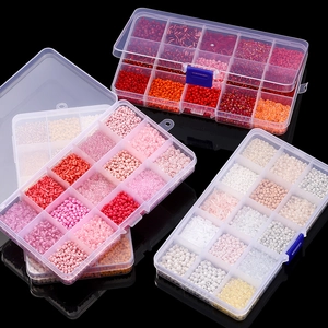 Close-up of three 15-grid boxes with red and pink glass seed beads for DIY jewelry