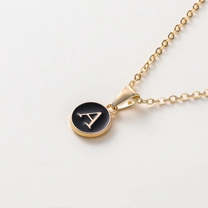 Détail d'un collier doré de 52cm avec pendentif en émail noir et lettre A dorée