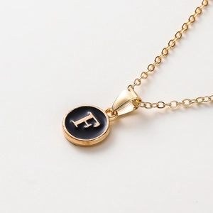 Détail du collier de 52cm avec pendentif disque doré et initiale lettre F en émail noir