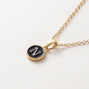 Vue macro d'un pendentif rond doré avec émail noir et la lettre N sur une chaîne fine