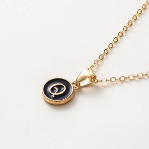 Vue macro d'un pendentif lettre Q doré à l'or fin avec émail noir sur chaîne