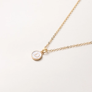 Détail d'une chaîne dorée de 52cm avec pendentif en émail blanc et la lettre D dorée