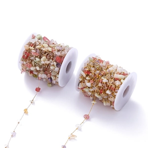 Macro shot of colorful natural gemstones hand-wrapped with fine gold wire on white spools