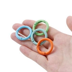 Bunte matte Metall-Federringe in Blau, Grün und Orange in der Hand gehalten für Größe