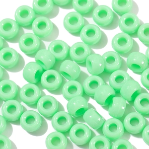 Close-up of mint green acrylic barrel beads with a glossy finish for DIY jewelry crafts