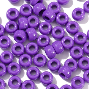 Macro detail of vibrant purple acrylic barrel beads with large holes for DIY jewelry