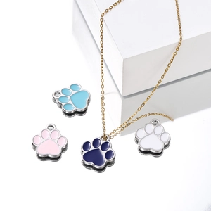 Emaille Pfotenanhänger in Blau, Rosa und Weiß mit Goldkette auf Spiegelfläche