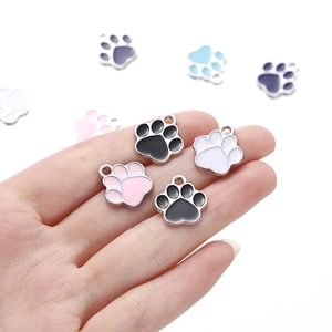 Hand hält bunte Emaille-Bärentatzen-Anhänger mit Metallringen für DIY-Schmuckherstellung