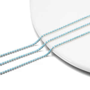 Close-up of 2mm light blue rhinestone claw chain with silver base on a white ceramic plate