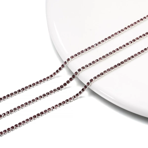 Detailed close-up of 2mm silver-plated claw chains with purple rhinestones on white ceramic