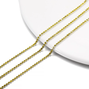 Close-up of 2mm yellow crystal rhinestone claw chains on white porcelain surface