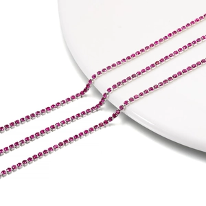 Macro detail of 2mm hot pink rhinestone tennis chain with silver metal base on white porcelain