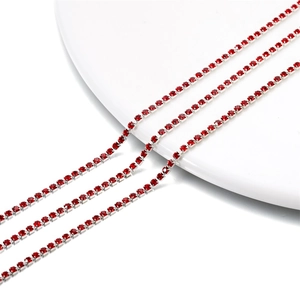 Macro shot of 2mm red crystal rhinestone cup chain with silver metal base on white porcelain