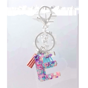 Détail du porte-clés lettre E en résine avec paillettes roses et pompon assorti