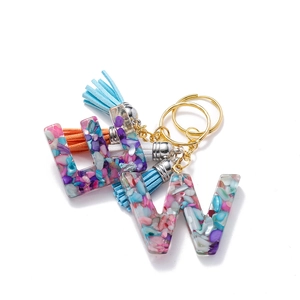 Détail du porte-clés DIY avec lettre W en résine, pierres colorées et pompons en suède