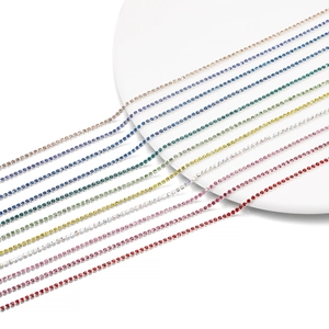Macro shot of 2mm multi-colored rhinestone claw chains arranged on a white platform
