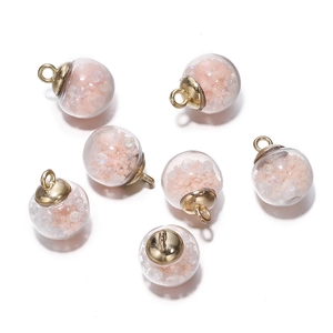 Detailed view of DIY luminous glass sphere charms with pink sequins and gold metal caps