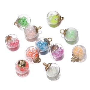 Close-up of colorful luminous glass ball pendants with gold caps for DIY jewelry