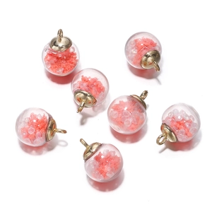 Detailed view of luminous coral pink glass ball pendants with gold caps for DIY jewelry