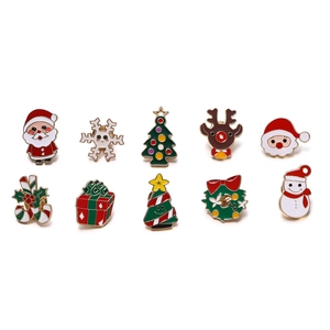 Flat lay detail of ten colorful Christmas enamel pins featuring Santa and reindeer motifs
