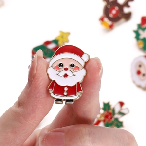 Macro view of hand-held Santa Claus enamel pin featuring detailed red metal craft