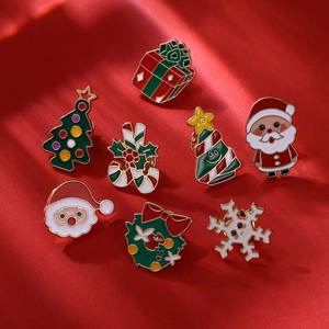 Flat lay of colorful enamel Christmas pins featuring Santa and trees on red fabric