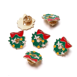 Detailed view of festive Christmas wreath pins with green enamel and butterfly clutch backings