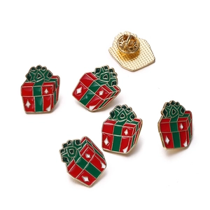 Detailed view of Christmas gift box enamel pins with gold trim and butterfly clutch backs