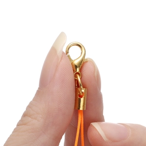 Detailed macro view of a gold lobster clasp with orange cord for DIY accessory making