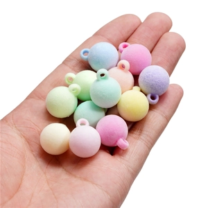 Main tenant des perles floquées macaron avec trous pré-percés pour la création de bijoux
