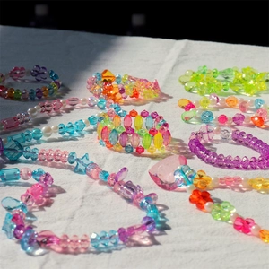 Detailed view of colorful DIY acrylic jewelry beads in heart and star shapes on white fabric