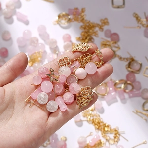 Macro view of pink glass crackle beads and gold alloy charms for DIY jewelry making