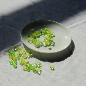 Detailed view of DIY green beaded jewelry set with acrylic beads in a ceramic tray