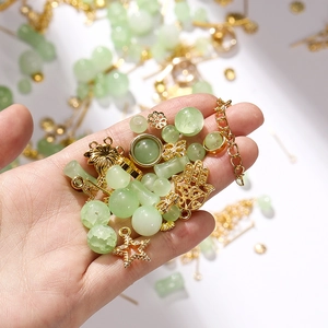 Macro view of light green crackle glass beads and golden alloy charms for DIY jewelry making