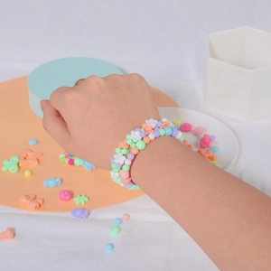 DIY macaron beaded bracelet set for girls featuring floral charms and pastel acrylic beads