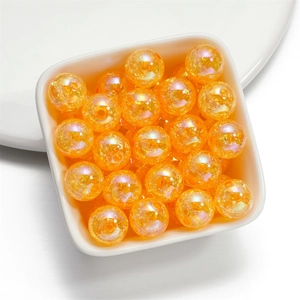 Macro view of 16mm orange iridescent cracked acrylic beads in a white square bowl