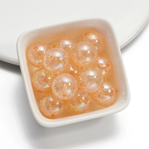 Macro view of 16mm orange translucent iridescent acrylic beads in a ceramic dish