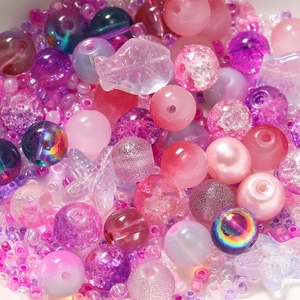 Macro detail of mixed pink and purple DIY glass beads in heart and star shapes