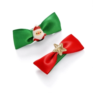 Close-up of festive Christmas bow hair clips with Santa Claus and golden star details